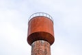 Rusty water tower against sky. Old water pump