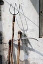 Rusty well used garden fork, scythe and hoe on the grunge wall