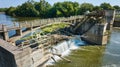 Rusty wheel and cogs on Maumee River Dam equipment beside waterfall chocked by trees and algae aerial Fort Wayne, IN Royalty Free Stock Photo