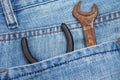 Rusty wrench and pliers are in the back pocket of jeans. Tool in special work clothes. Close-up.