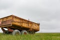 Rusty yellow farm tractor wagon in green landscape Royalty Free Stock Photo