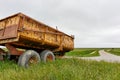 Rusty yellow farm tractor wagon in green landscape Royalty Free Stock Photo