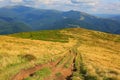 Rut road across mountains meadow Royalty Free Stock Photo