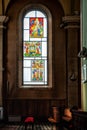 Stained glas window in church with empty seats Royalty Free Stock Photo