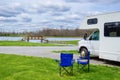 RV camper and chairs in camping, family vacation travel, holiday trip by motorhome Royalty Free Stock Photo