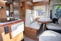 Rv Camper Dining Room area with wooden white luxury interior in motor home van during vanlife Royalty Free Stock Photo