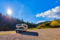 RV camper parked on rocky beach next to forest of Russian River