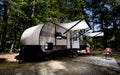 Campter trailer camped in a forest with awnings extended