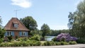 Red house with blue and white windows, beautiful purple flower bush in the foreground Royalty Free Stock Photo