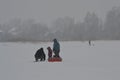 Rybinsk, Russia - January 04 2021: Father, mother and child on winter fishing on frozen lake in winter stormy weather