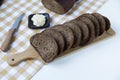 Rye bread is cut into slices on a wooden board on a light background, near butter, a knife, a loaf of bread Royalty Free Stock Photo