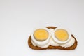 Rye bread sandwich with two halves of boiled egg with white sauce on white background Royalty Free Stock Photo