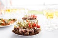 Rye bread sandwiches, canapes, bruschetta on white plate. solemn banquet. Lot of glasses champagne or wine on the table Royalty Free Stock Photo