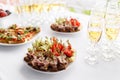 Rye bread sandwiches, canapes, bruschetta on white plate. solemn banquet. Lot of glasses champagne or wine on the table Royalty Free Stock Photo