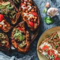 Rye bread toasts with goat cheese, tomatoes on plate on blue background with baked sweet potato toasts with roasted chickpeas,