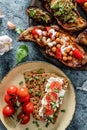 Rye bread toasts with goat cheese, tomatoes, seedlings on plate on blue background with baked sweet potato toastes with roasted