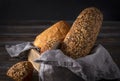 Rye grain bread in a basket with a napkin on a dark background, wheat loaf