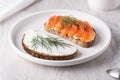 Rye sandwich with salmon and cream cheese on white wooden table