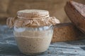 Rye sourdough in glass jar and loaf of whole grain bread, yeast-free leaven starter for handmade organic bread Royalty Free Stock Photo