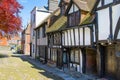 High street of Old Rye town with periodic buildings, lots of people and cars parked on side.