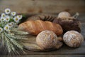 Rye and wheat fresh hot bread with ears and a bouquet of daisies on a wooden rustic background, close-up. Royalty Free Stock Photo