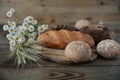 Rye and wheat fresh hot bread with ears and a bouquet of daisies on a wooden rustic background, close-up. With copy space for text Royalty Free Stock Photo