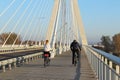 Rzeszow, Poland - 9 9 2018: A guy with a girl riding bicycles on a suspension road bridge across the Wislok River on a sunny, clea