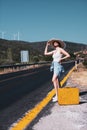 20s age One woman with a straw hat hitchhiking by the country roadside Royalty Free Stock Photo