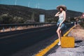 20s age One woman with a straw hat hitchhiking by the country roadside Royalty Free Stock Photo