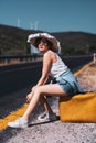 20s age One woman with a straw hat hitchhiking by the country roadside Royalty Free Stock Photo