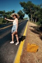 20s age One woman with a straw hat hitchhiking by the country roadside Royalty Free Stock Photo