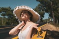 20s age One woman with a straw hat hitchhiking by the country roadside Royalty Free Stock Photo