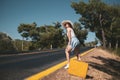 20s age One woman with a straw hat hitchhiking by the country roadside Royalty Free Stock Photo