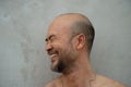 30-40s bald or skin head beard Japanese laughing happy man with grey cement background Royalty Free Stock Photo