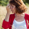 50s brunette woman massaging nose to soothe sinus pain outdoors