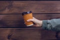 It`s coffee time! Woman`s hand holding paper cup of fresh coffee against dark wooden background taleawat take away takeout paper Royalty Free Stock Photo