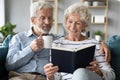 65s spouses resting at home reading book drinking beverage Royalty Free Stock Photo