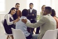 Friends, coworkers or patients in group therapy comforting sad young black woman