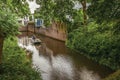 Boat with people navigating the canal surrounded by walls and lush vegetation in s-Hertogenbosch. Royalty Free Stock Photo