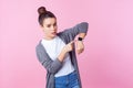 It`s late. Portrait of worried brunette teenage girl pointing at wristwatches checking time. studio shot isolated on pink