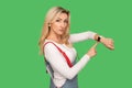 It`s late, time to go! Portrait of bossy strict adult woman pointing at wrist watch and looking with displeased expression