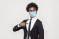 It`s me. Portrait of proud young handsome worker man in black suit with surgical medical mask standing pointing himself and Royalty Free Stock Photo