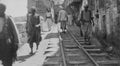 1920s monochrome photo of a street scene with people walking on the railway line, at the Quay in Jaffa in Palestine, now Israel.