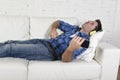 20s or 30s man having fun lying on couch listening to music on mobile phone with headphones playing air guitar Royalty Free Stock Photo