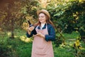 30s Woman in hat tasting red wine in vineyard. Portrait of pretty young woman holding bottle of wine on sunny day Royalty Free Stock Photo