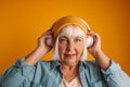 Portrait of mature 50s woman headphones listen to music sing song record voice by mobile cell phone dictaphone on yellow Royalty Free Stock Photo