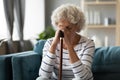 70s woman hides her face with hands holding walking stick Royalty Free Stock Photo