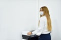 30s woman office Manager in a face mask makes copies of documents on a copier Royalty Free Stock Photo