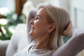 60s woman put hands behind head resting indoors enjoy weekend Royalty Free Stock Photo