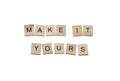 Wooden letters with black capital letters with the phrase `Make it yours` on white background